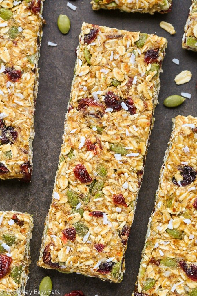 granola bars with nuts and dried cranberries are lined up on a baking sheet