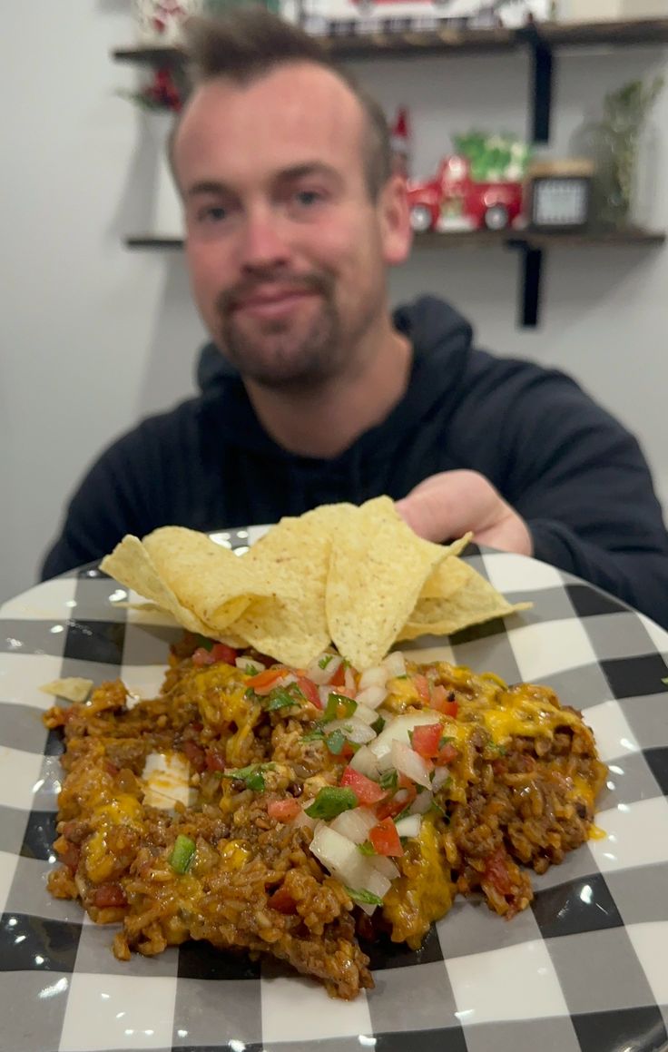 a man sitting at a table in front of a plate with some food on it