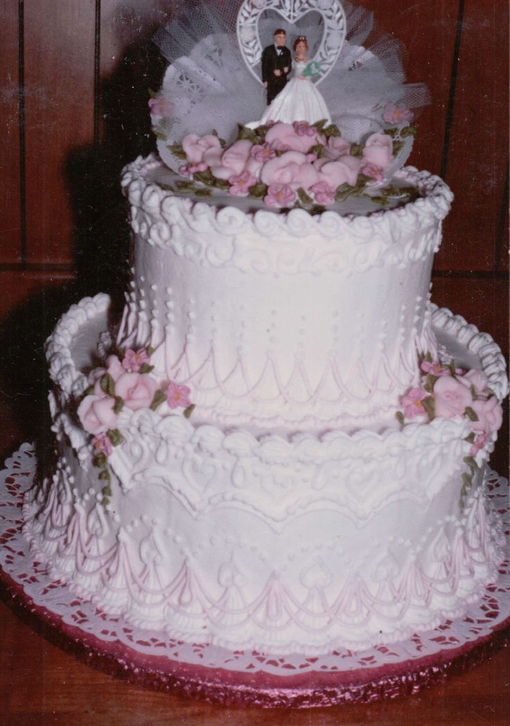 the wedding cake is decorated with pink flowers and a bride and groom figurine