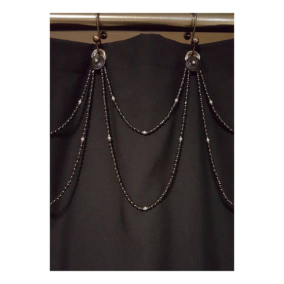 a black shirt with silver chains hanging from it's back end and two beads attached to the side