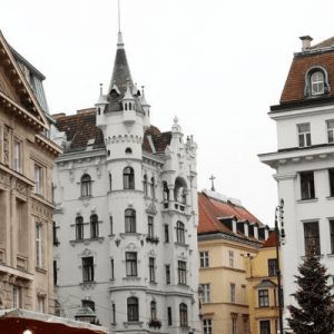 the buildings are all white and brown in this city area with people walking around them