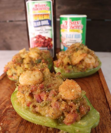 stuffed bell peppers on a wooden cutting board with two cans of pepper paste in the background