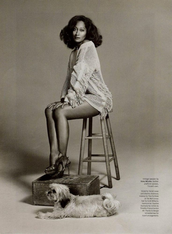 a black and white photo of a woman sitting on a stool with a dog next to her