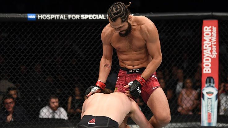 a man in red shorts standing next to another man with boxing gloves on his feet