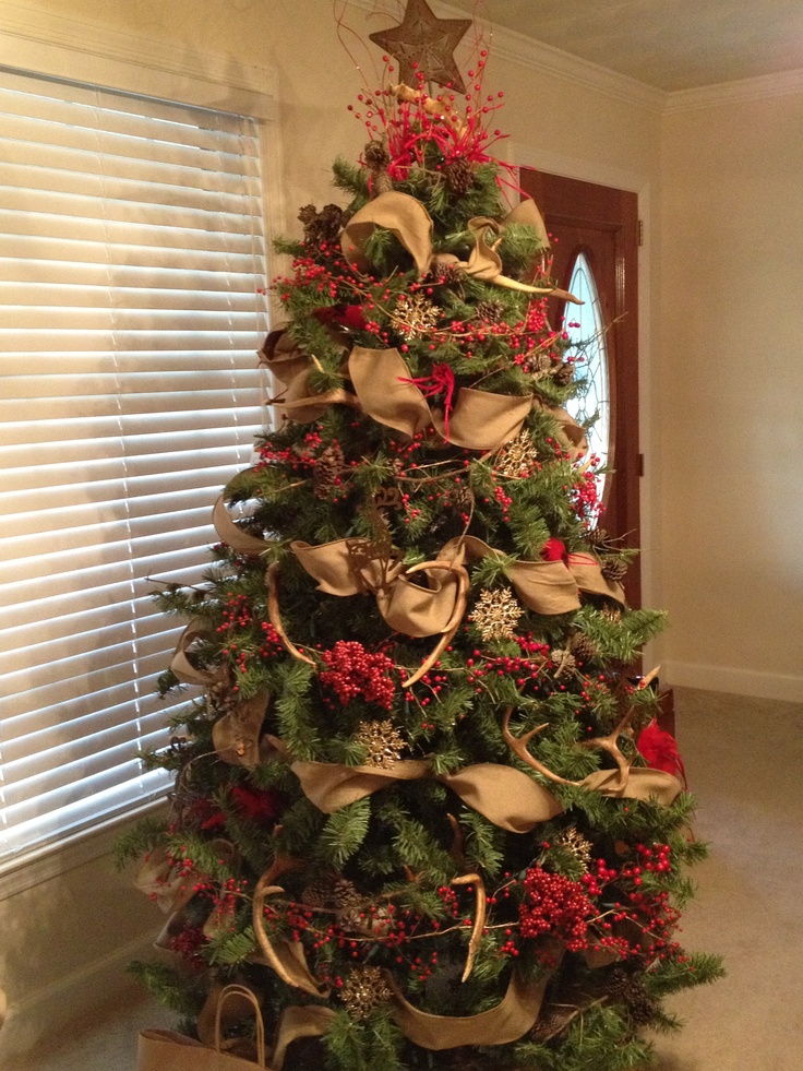 a christmas tree is decorated with gold and red ribbons, poinsettis and bows