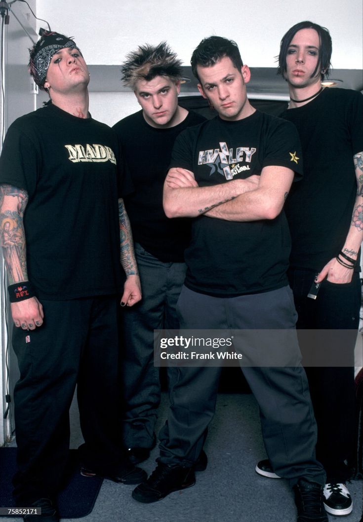 five men standing in front of a wall with their arms crossed and tattoos on them