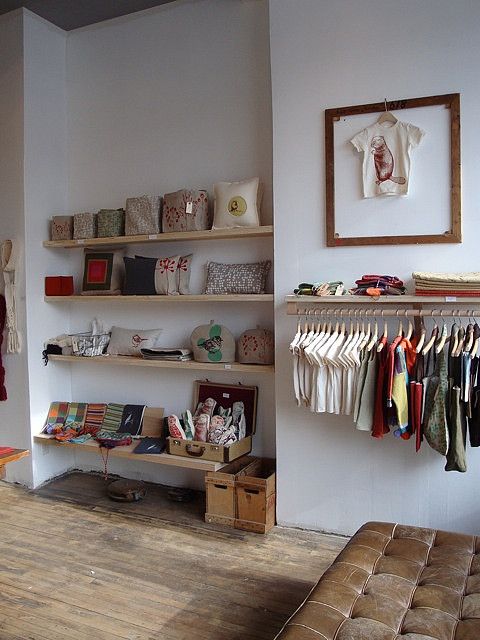 a living room filled with furniture and lots of clothes hanging on the wall next to a couch