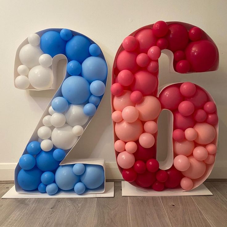 the number twenty six made out of balloons is displayed in front of a white wall