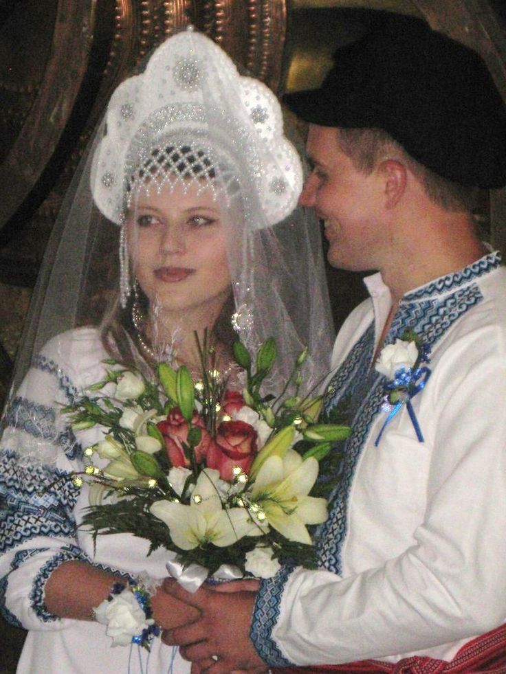 a man and woman dressed in traditional german garb, holding bouquets of flowers