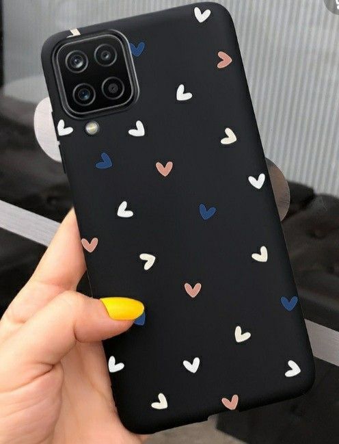 a woman holding up her phone case with hearts on the back and yellow nail polish