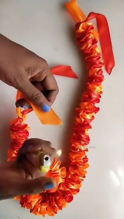 someone is making an orange flower wreath with scissors