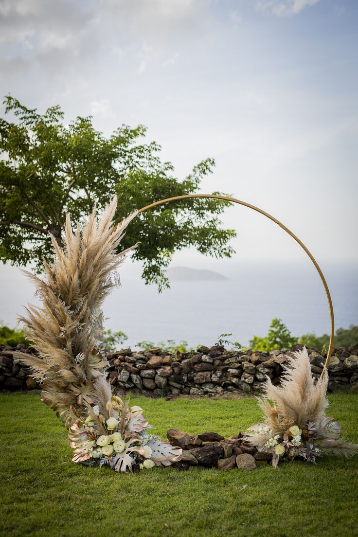 a wedding arch decorated with pamodia and pamodia flowers in front of the ocean