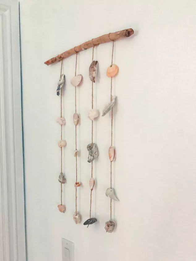 a wall hanging made out of shells and driftwood is hung on the wall next to a door