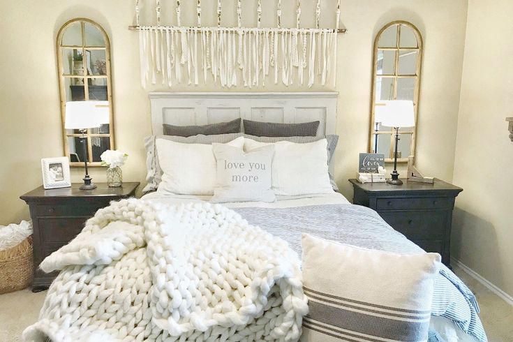 a bed with pillows and blankets on top of it next to two mirrors in a bedroom