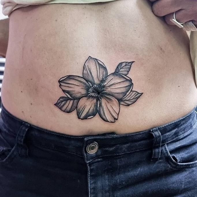 a woman's stomach with a flower tattoo on her belly and the bottom part of her stomach