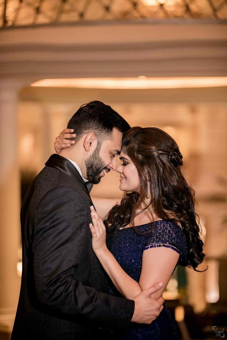 a man and woman standing next to each other in front of a chandelier