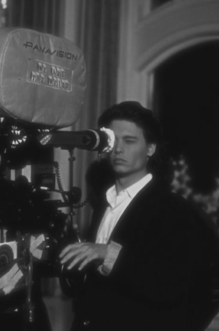 a man standing next to a camera on top of a tripod