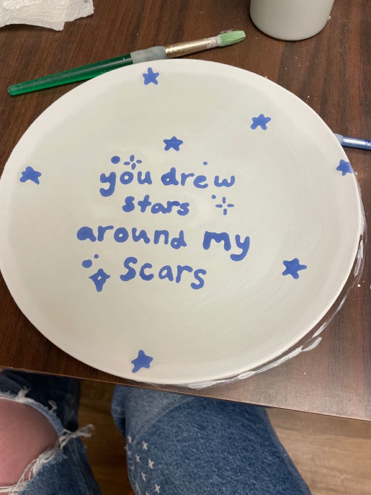 a white plate with blue writing on it that says you drew stars around my scars