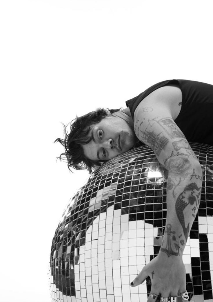 a man laying on top of a disco ball with his arms stretched out and eyes closed