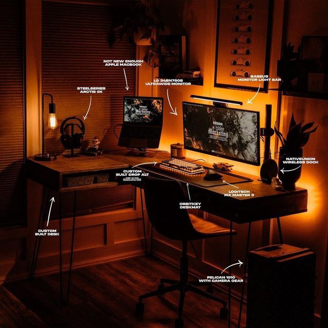 a desk with a computer monitor and keyboard on it in a room that is dimly lit