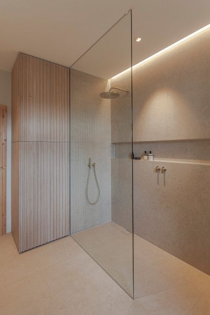 a bathroom with a glass shower door and beige walls