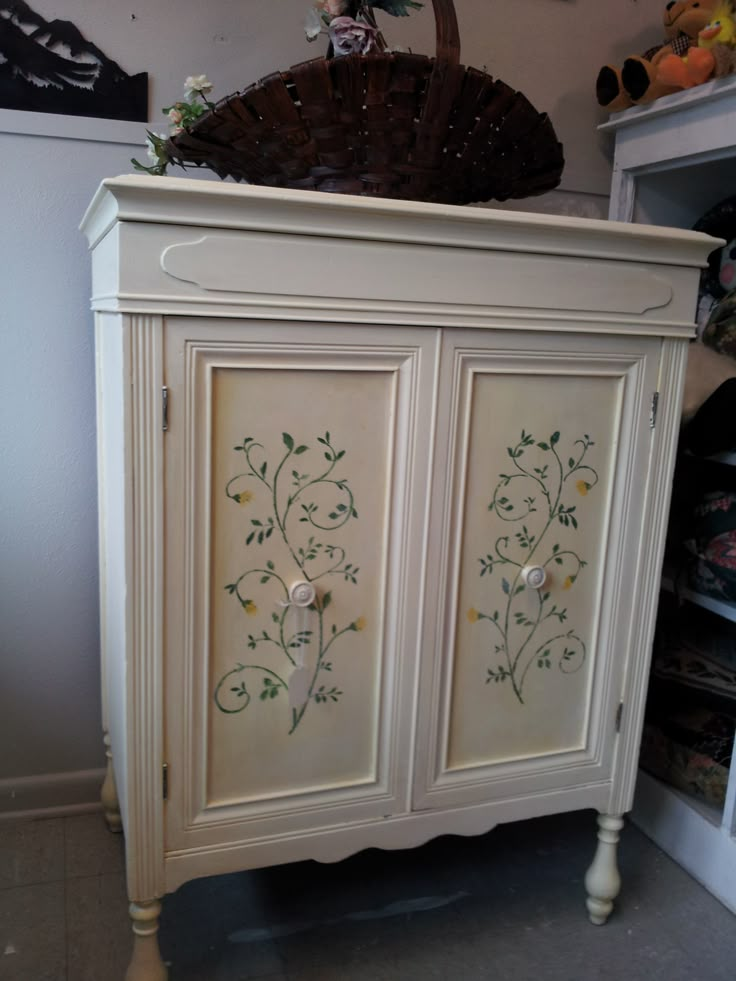 a white cabinet with floral designs painted on it