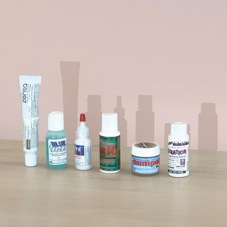 several different types of skin care products lined up on a wooden table against a pink wall