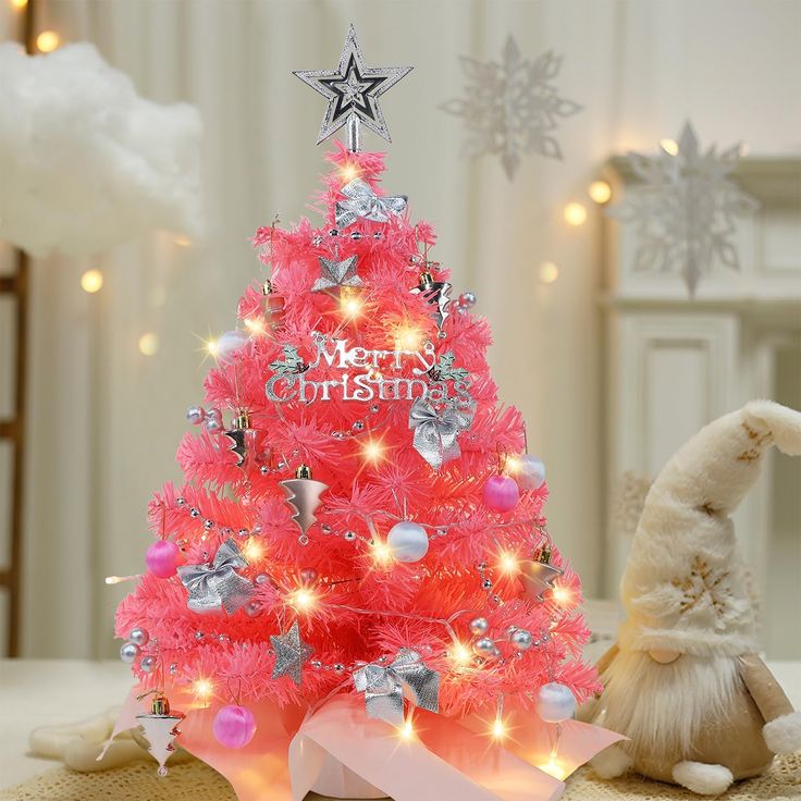 a pink christmas tree decorated with lights and ornaments