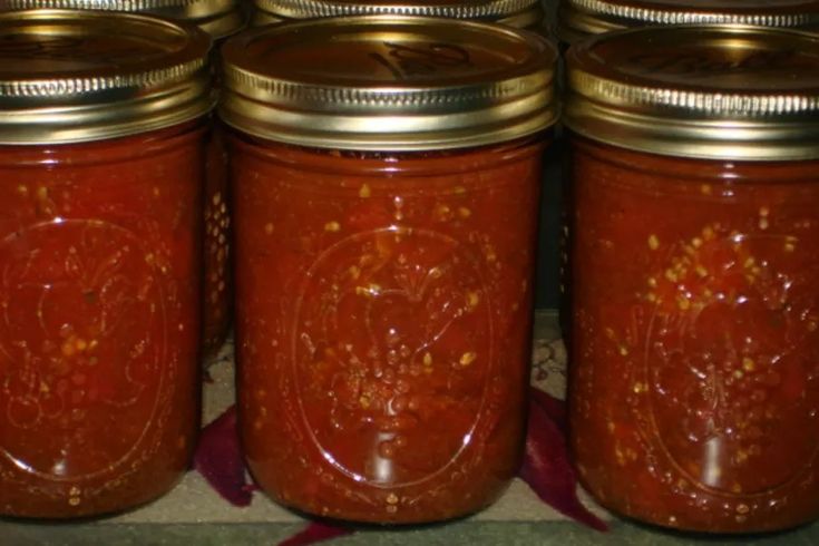 four jars filled with red liquid sitting on top of a counter