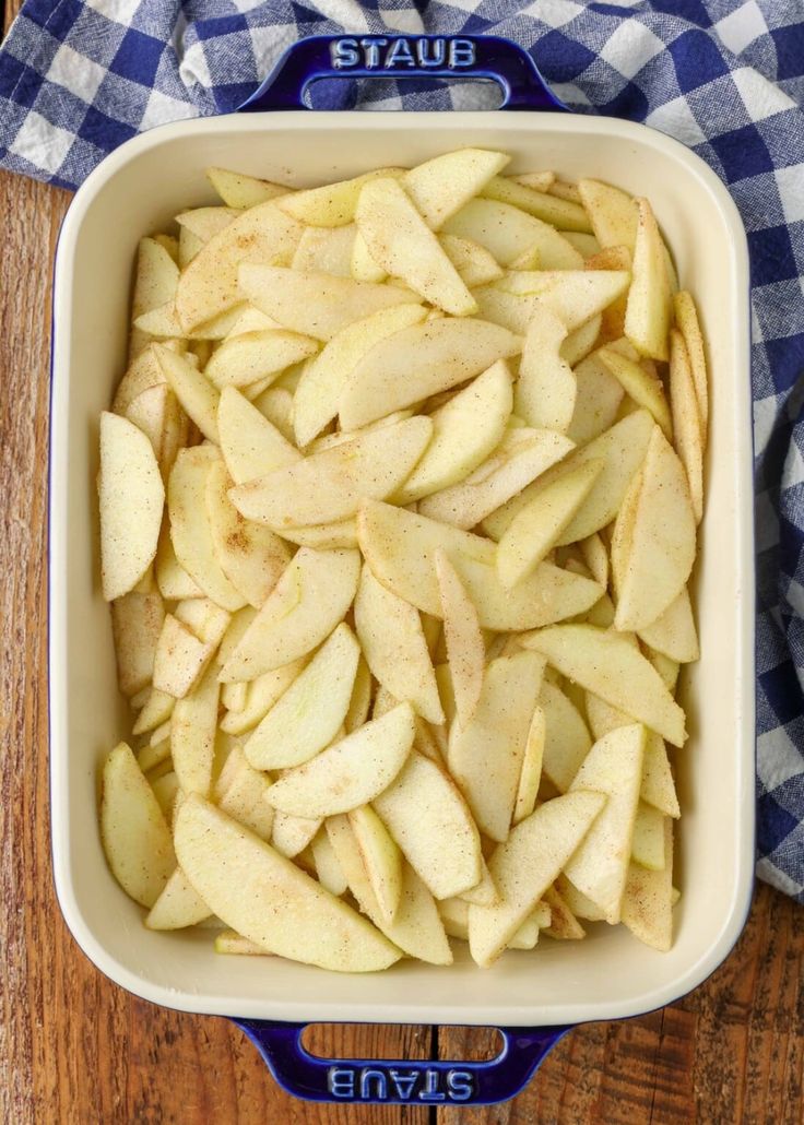 sliced apples in a baking dish on a wooden table