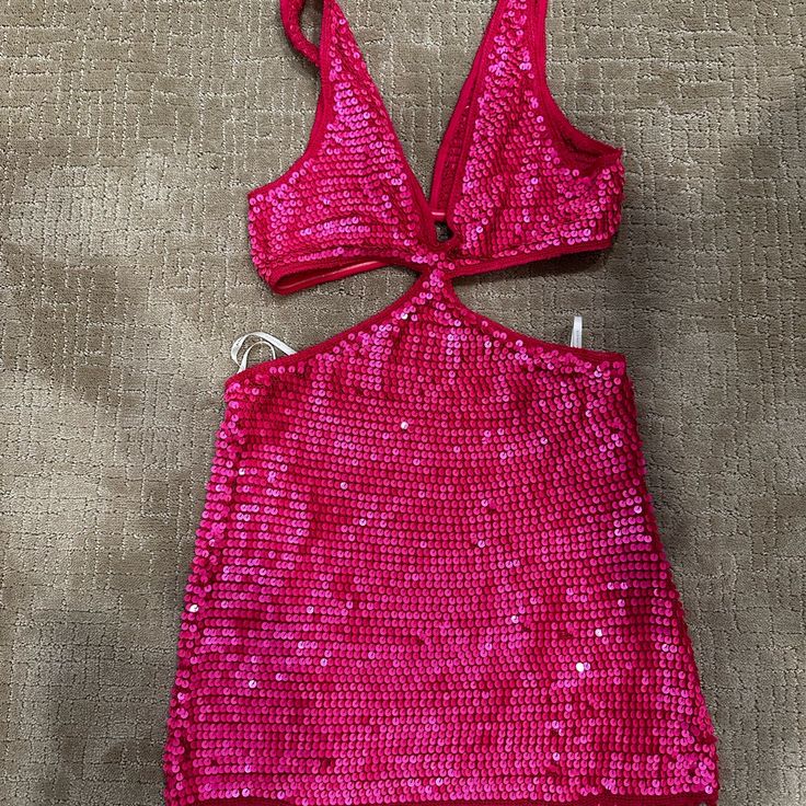 a pink top with sequins is laying on the ground next to a pair of scissors