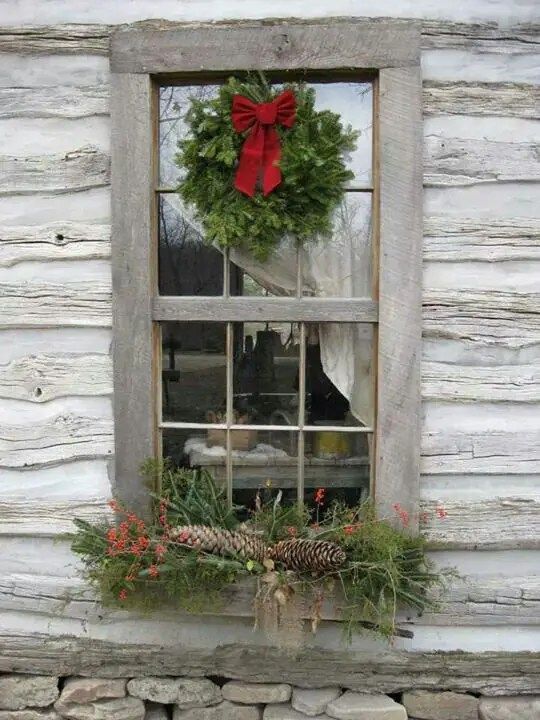 an old window is decorated with wreaths and pine cones