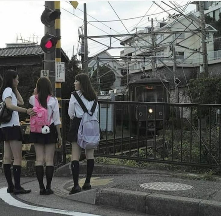 three girls are standing on the street corner