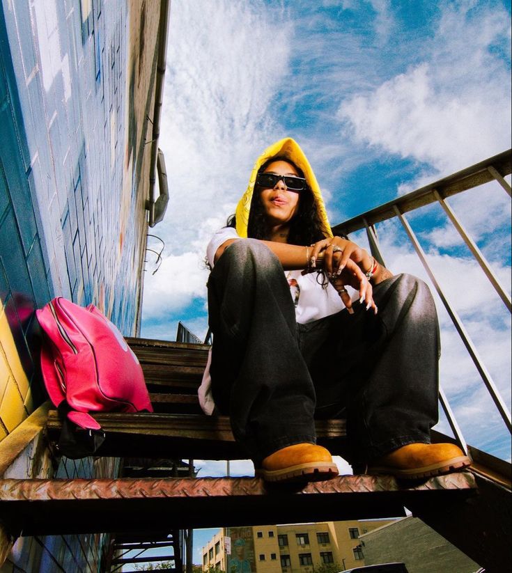 a woman sitting on top of a wooden bench next to a tall building in the city