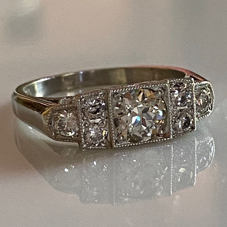 Details: Sweet vintage inspired Art Deco Style diamond and platinum step ring with just under 1 carat of diamonds! This ring has so much sparkle, and life--hard to capture in a photo but it shines bright! This ring was designed by our amazing jeweler Scott Eerkes, and lovely vintage diamonds. Would make a fabulous engagement or wedding ring! Would look great in a ring stack! This ring comes with an appraisal. Appraisal: Cut: European Carat Weight: 0.59 carat (Estimated) Measurements: 5.40 x 3.14 Classic Platinum Cluster Ring With Baguette Cut, Dazzling Diamond White Platinum Diamond Ring, Art Deco Platinum Diamond Ring With Brilliant Cut, Dazzling Diamond Cut Platinum Cluster Ring, Timeless Platinum Diamond Ring With Single Cut Diamonds, Dazzling Platinum Cluster Ring With Diamond Cut, Classic Platinum Cluster Ring With Vvs Clarity, Art Deco Platinum Diamond Ring In Diamond White, Art Deco Platinum Diamond Ring With Vvs Clarity