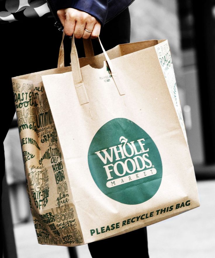 a person carrying a bag with the words whole foods on it