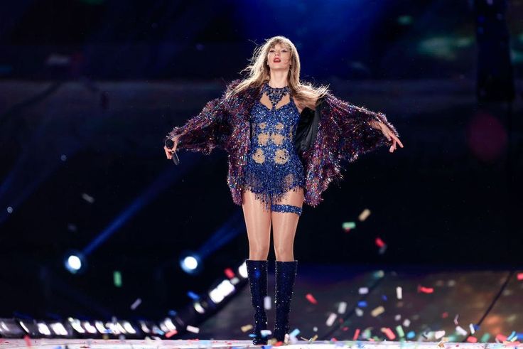 a woman in a blue dress on stage with confetti falling around her legs