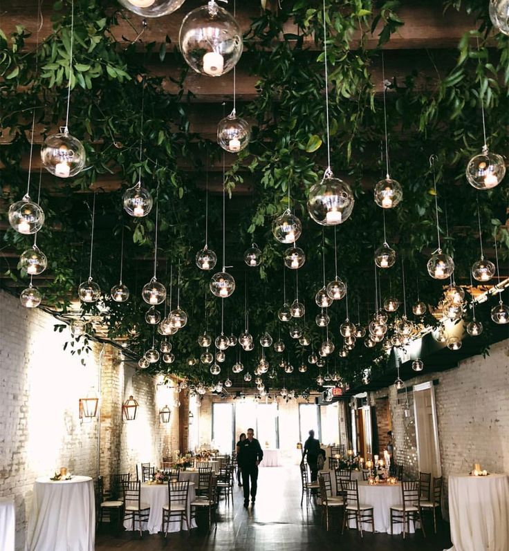 an indoor wedding venue with hanging lights and greenery