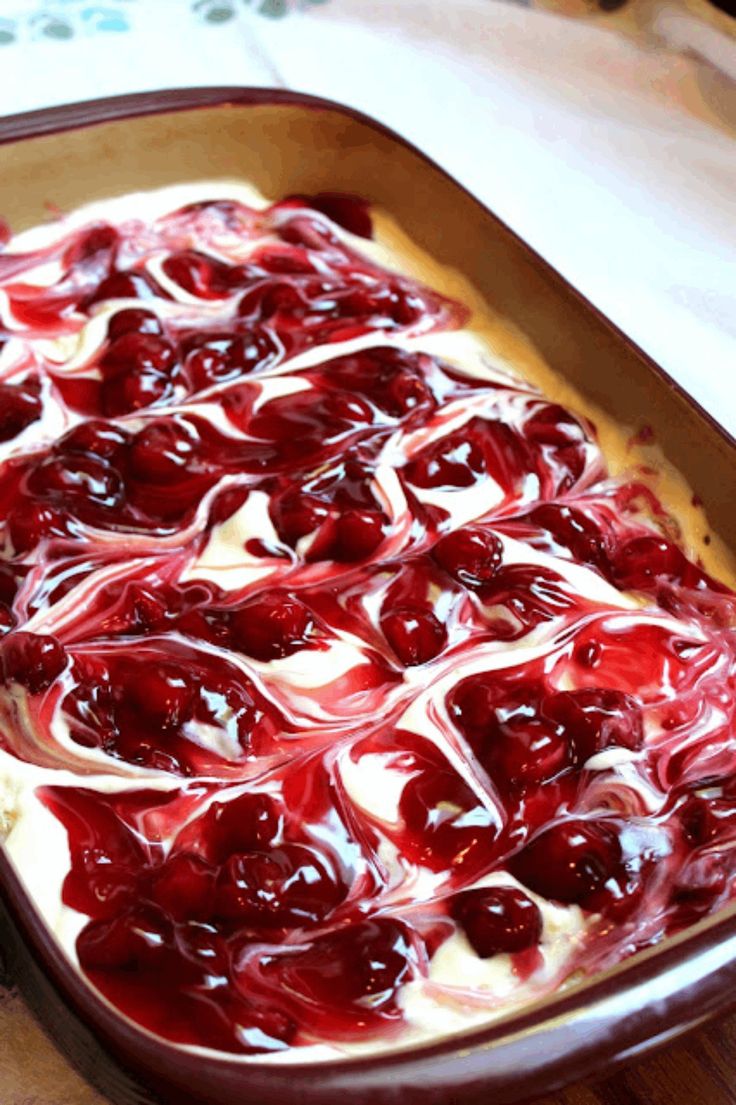 an uncooked dish with cherries and cream in it