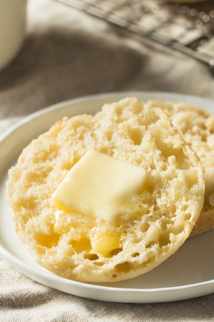 two biscuits with butter are on a white plate