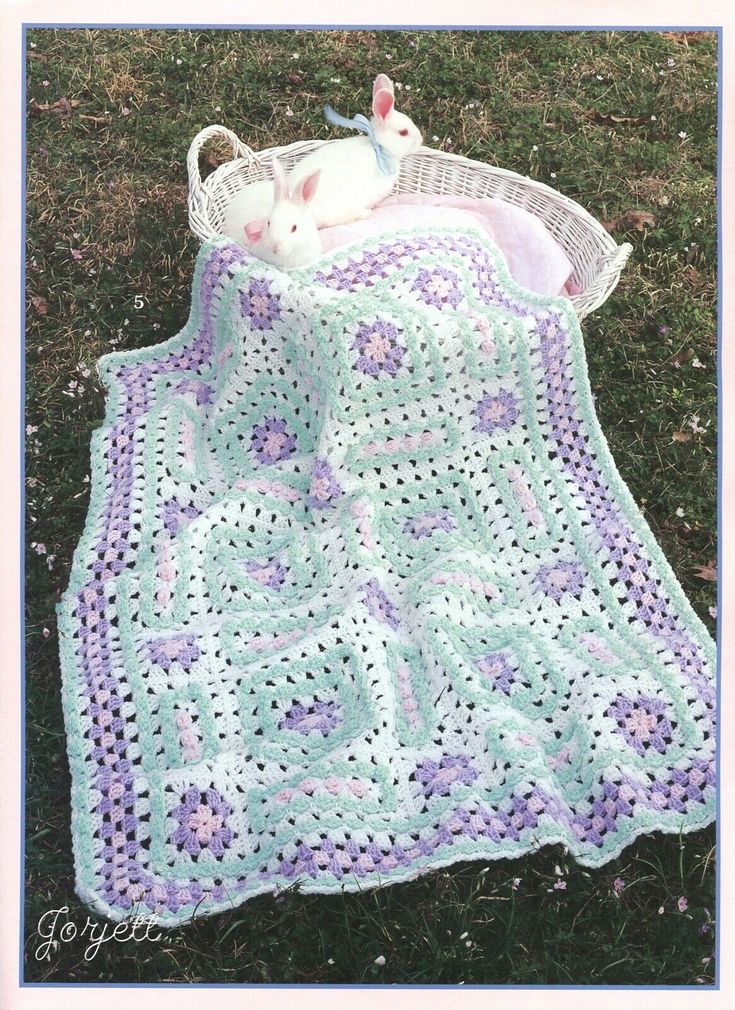 a crocheted blanket on the ground with a stuffed animal in it