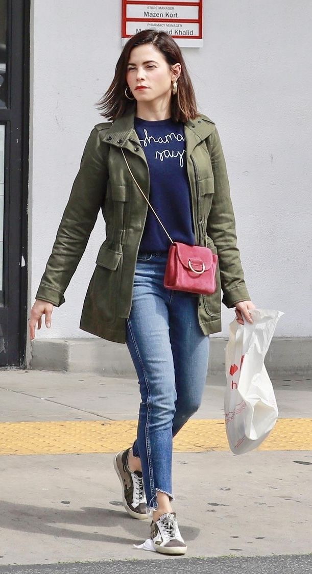 a woman is walking down the street with her hand in her pocket and holding shopping bags