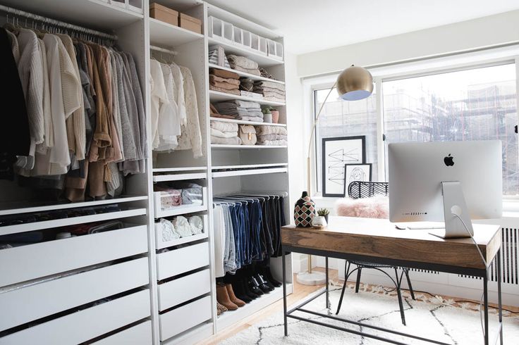 an organized closet with clothes and computer on the desk