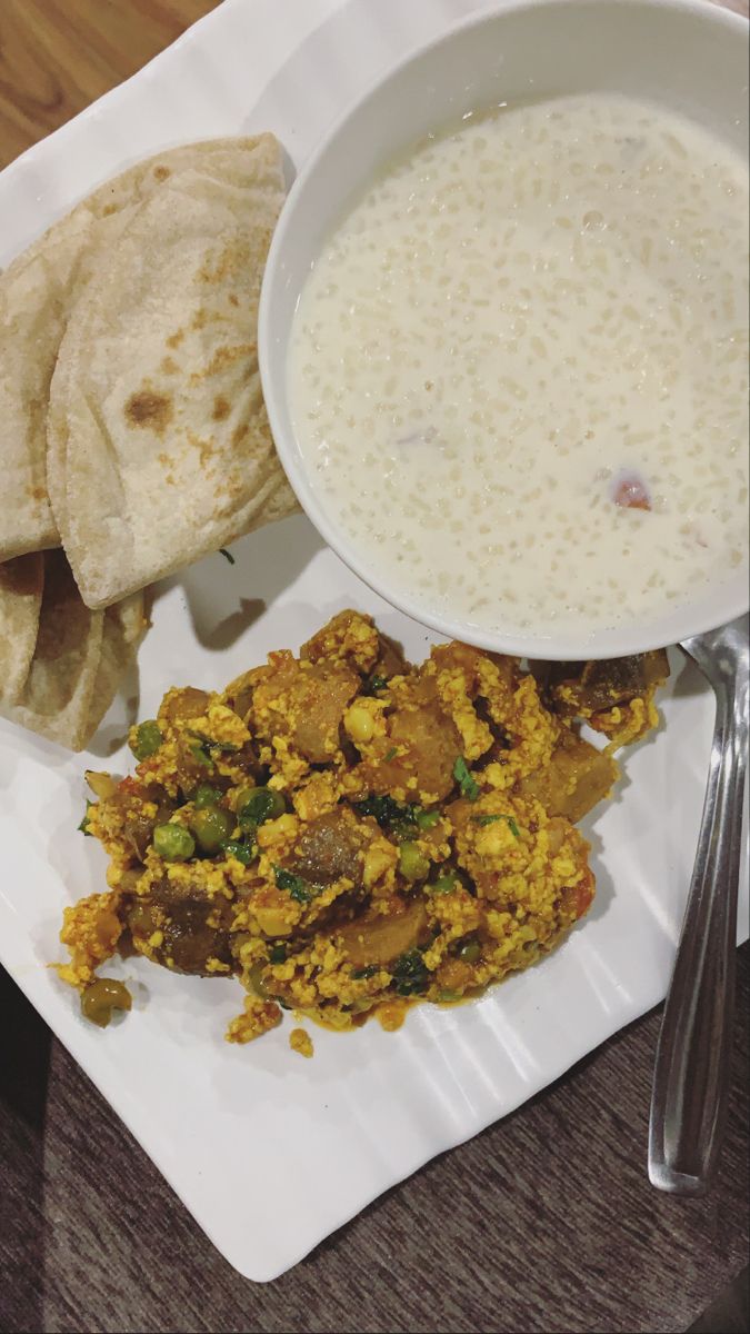 a white plate topped with food next to pita bread