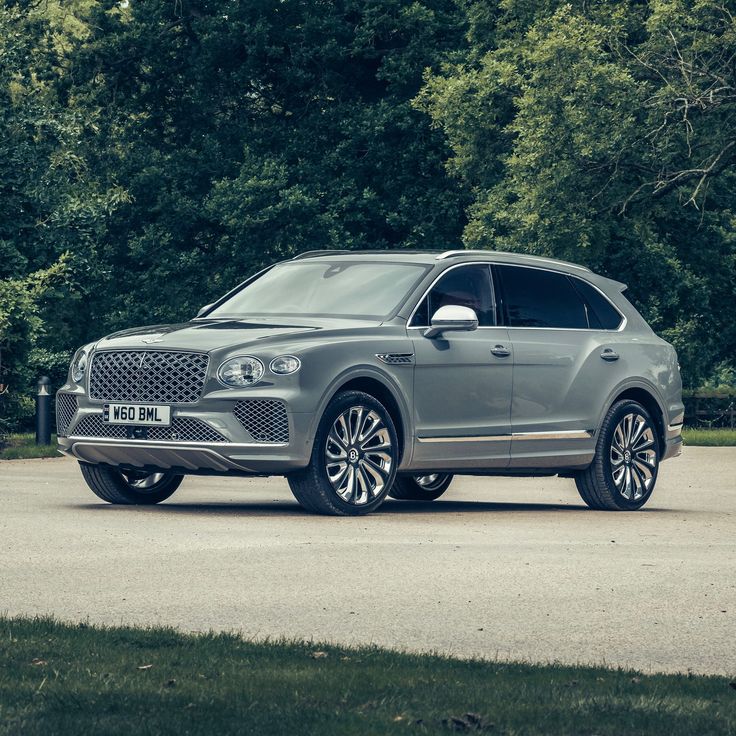 a grey suv parked in front of some trees