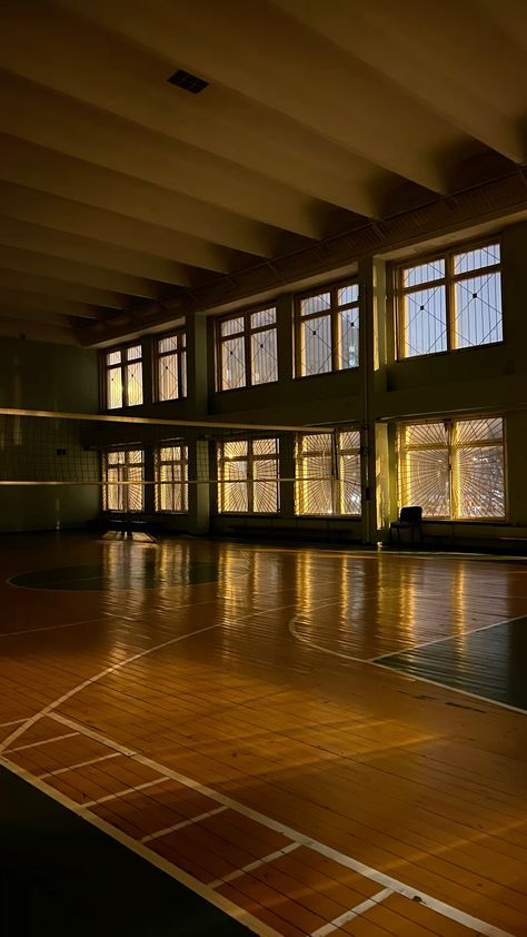 an empty basketball court with lots of windows and wood flooring in the middle of it