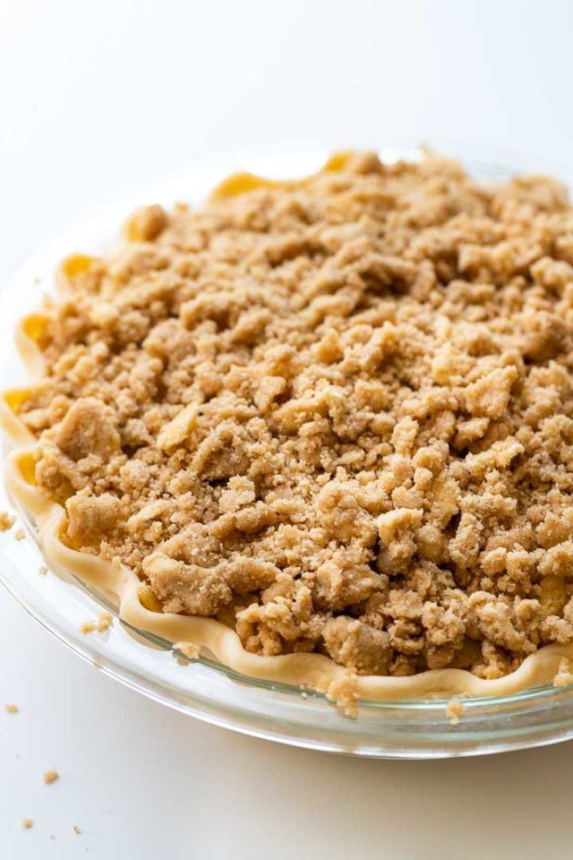 an uncooked pie sitting on top of a glass plate covered in crumbs