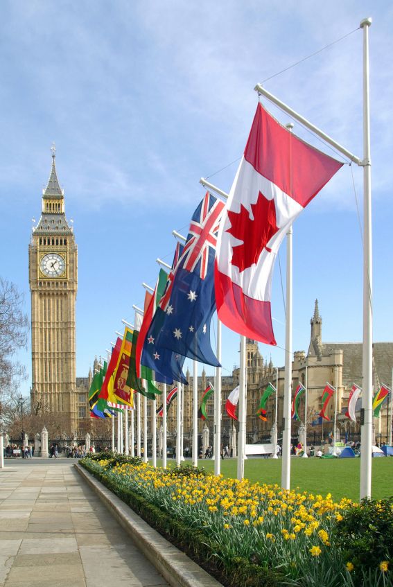 many flags are flying in front of the big ben clock tower and flowers on display