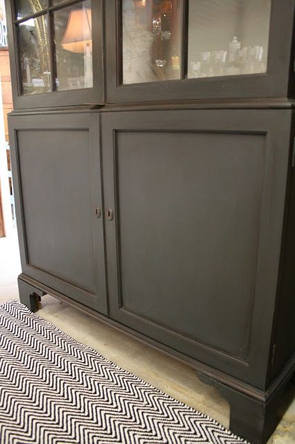 a black china cabinet sitting on top of a rug