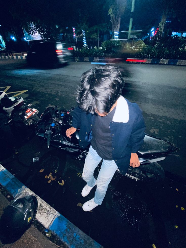 a young child standing on the back of a motorcycle at night with it's lights on